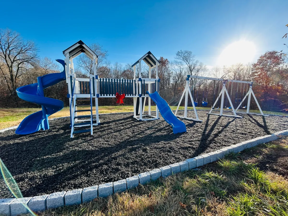 An exterior shot showcasing a lively playground with slides and swings, surrounded by green outdoor space. The area is bright and welcoming, highlighting opportunities for recreation and relaxation in the neighborhood.