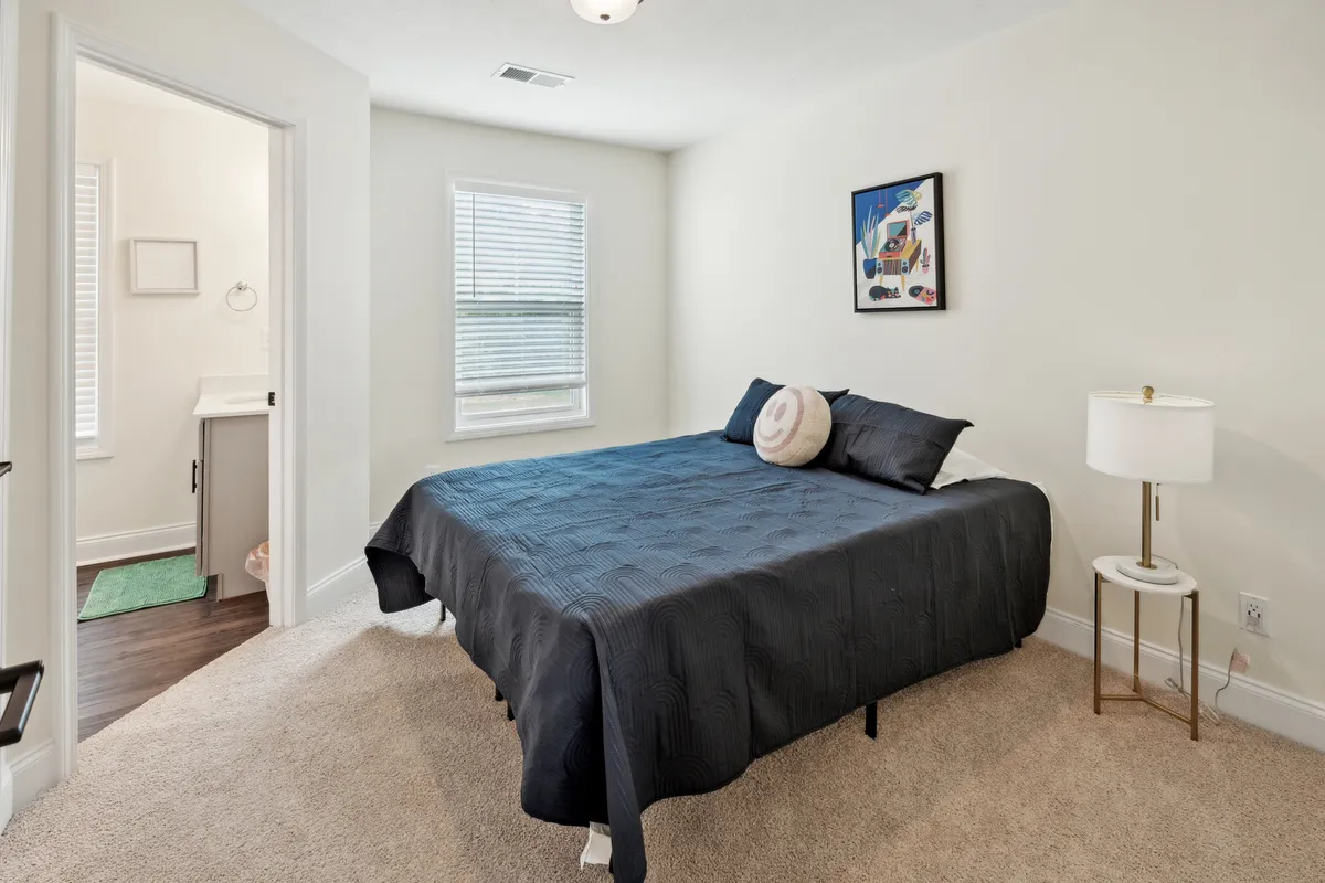 A cozy bedroom with a comfortable bed, soft lighting, and tasteful wall art. The ambiance is calm and inviting, creating a sense of restful retreat ideal for business travelers.