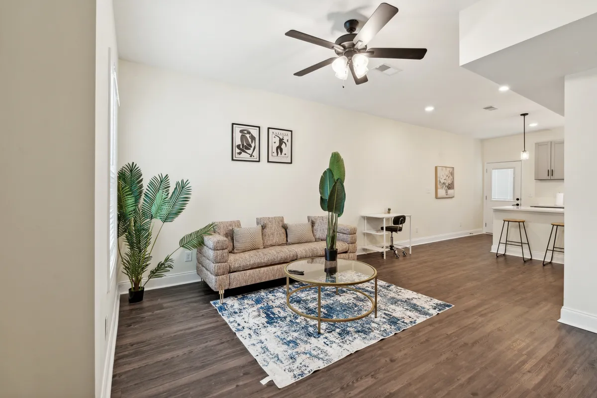 The image showcases a modern, inviting living room with a plush sofa, stylish coffee table, soft area rug, vibrant houseplant, and eye-catching artwork. The space exudes warmth and comfort, perfect for gatherings or quiet moments.