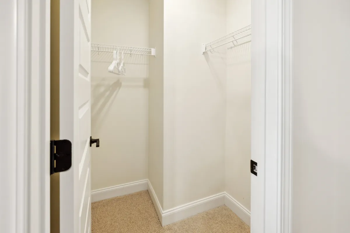 This image captures a minimalist and functional entryway with empty shelving and a doorway leading out. The space is uncluttered, allowing for easy movement and offering ample storage for belongings right as you enter the home.